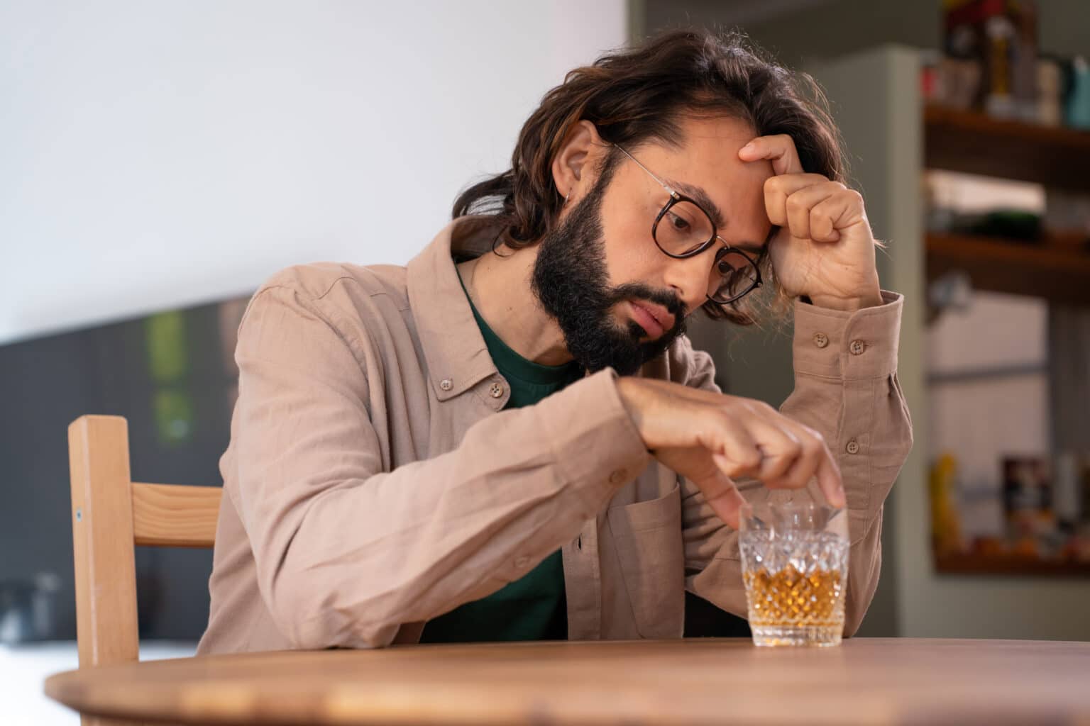 A man looking down at a glass of alcohol wondering does alcohol abuse cause diabetes​.