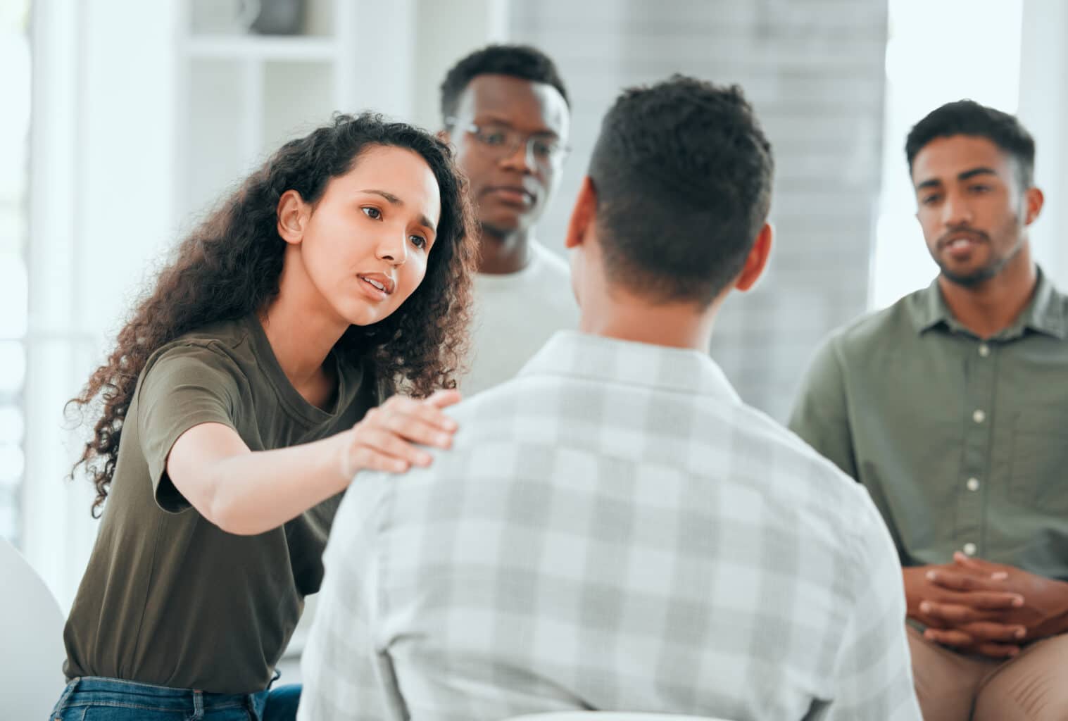 A woman placing her hand on a man's shoulder in support in a group setting for the topic what is an interventionist.