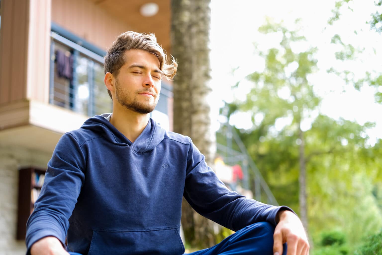 A young man meditating in a park for the topic how to control your emotions.
