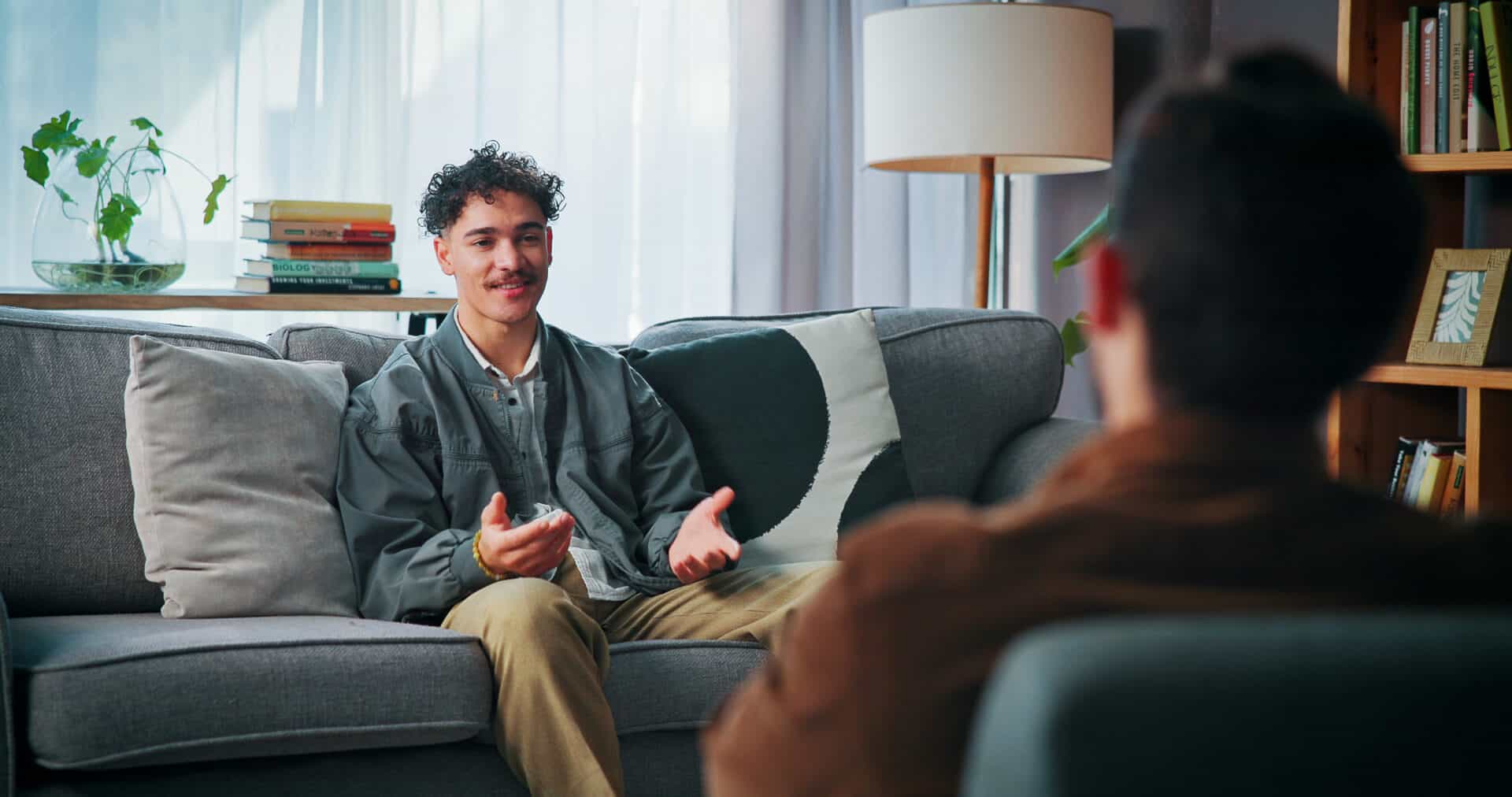 A young man speaking with a therapist for the topic cost of long term rehab for young adult men.