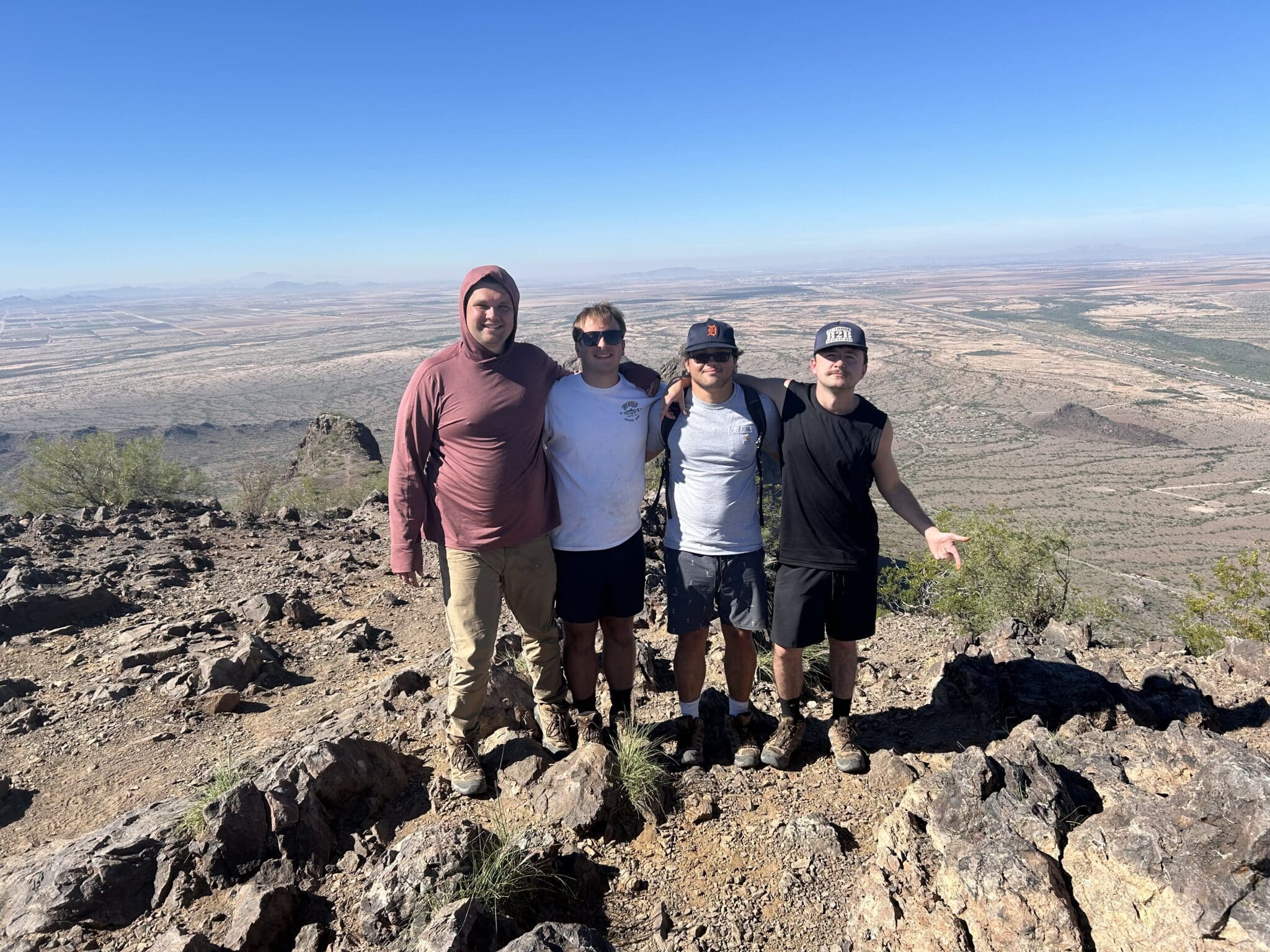 Four young men posing on top of a mountain.